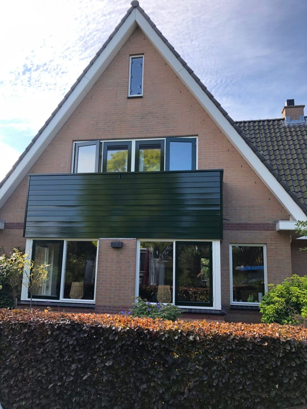 Buitenschilderwerk: gevel met groene gevelplaat en houten kozijnen, afgewerkt door P. Verberg