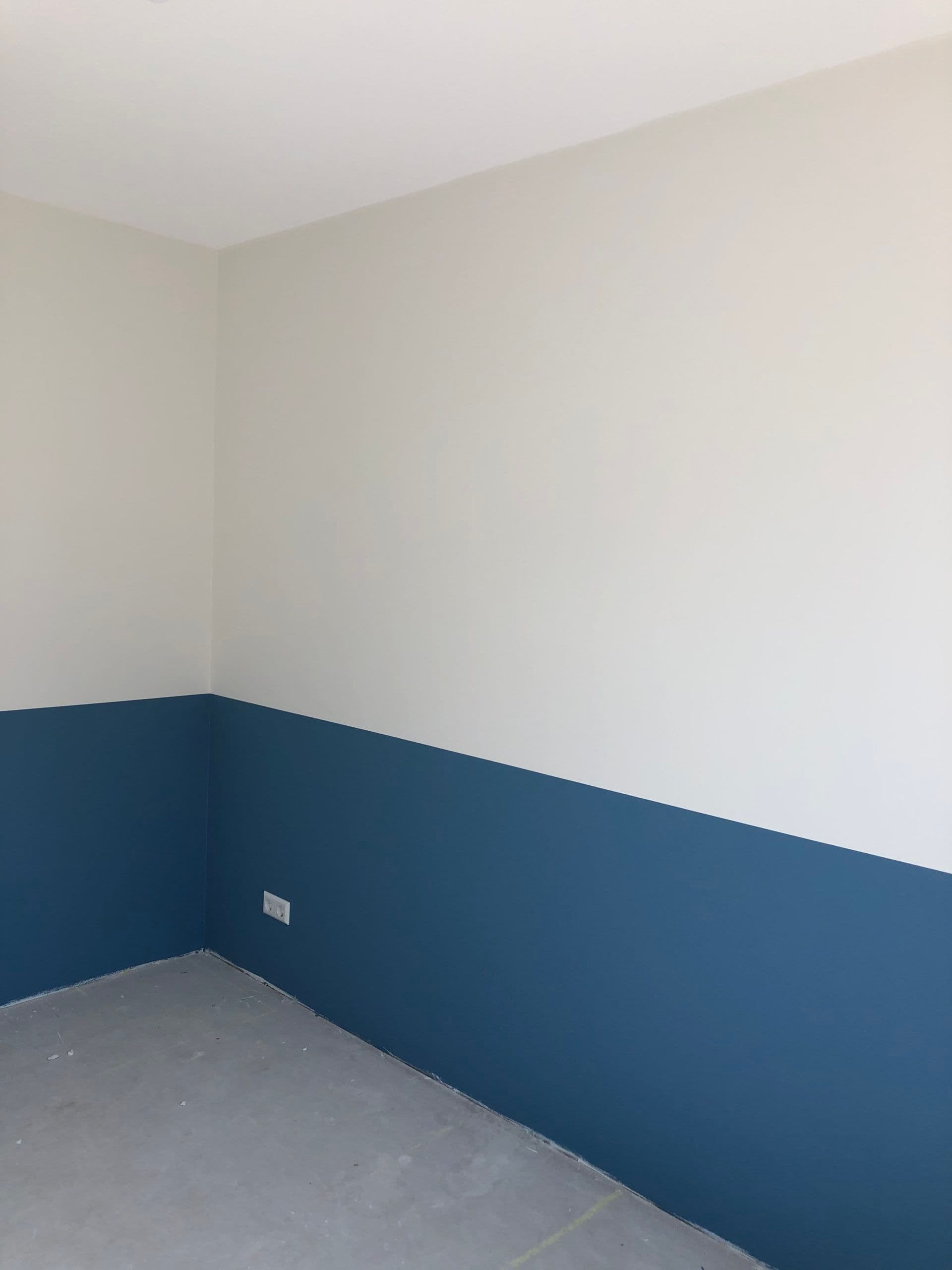 Strakke wanden met donkerblauw onderschilderwerk in een woonkamer in Leiderdorp